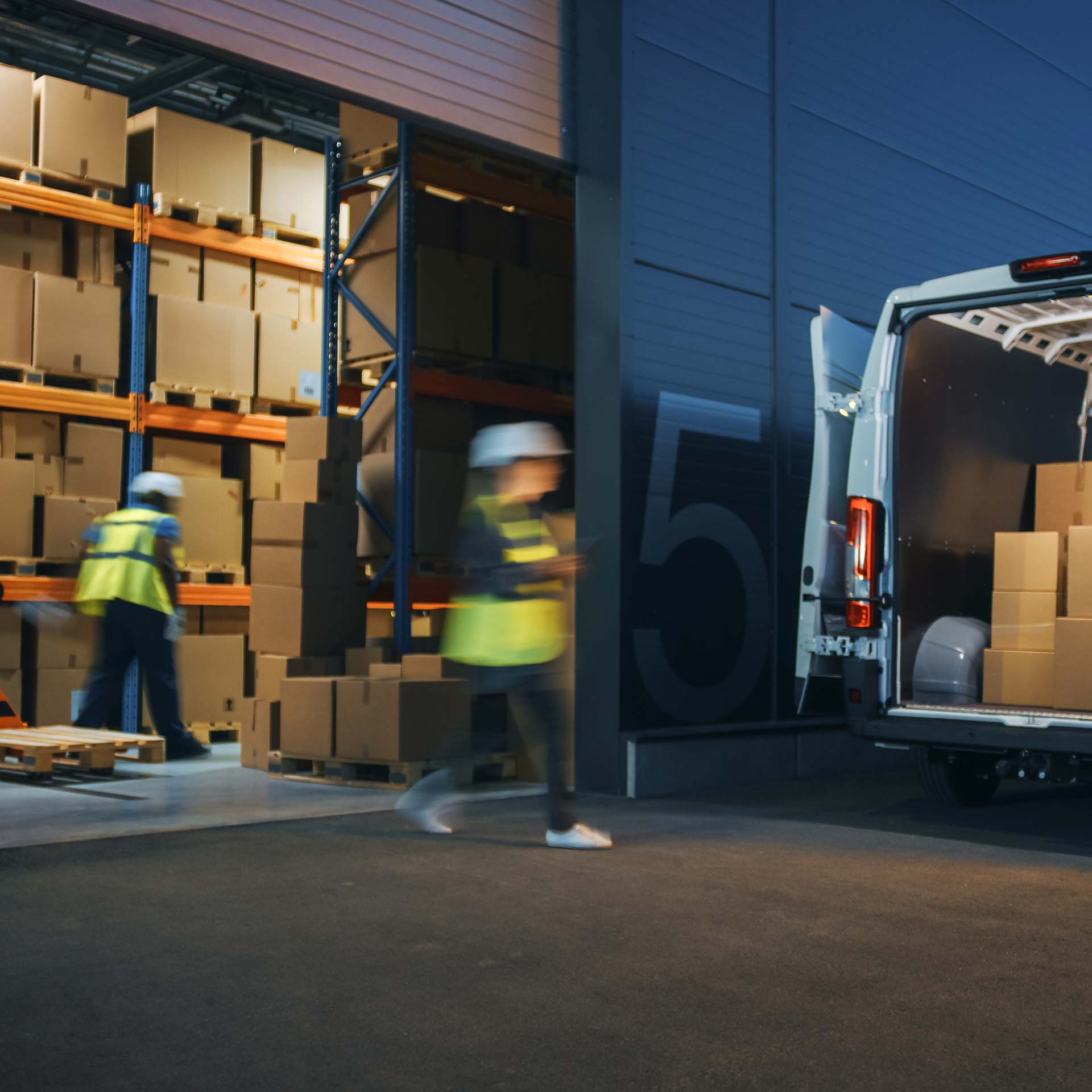 employees in saftey vests loading a delivery van from the warehouse